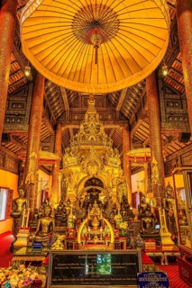 Sumptuous interior with richly decorated wooden ornaments, gilded Buddha statues, Buddhist temple