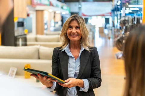Smiling professional saleswoman holding a tablet and assisting customers in a modern home