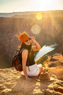 Woman backpacker sitting on a rock admiring the stunning panoramic view of horseshoe bend canyon,