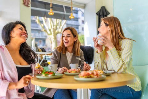 Three diverse women friends enjoying a fun gathering and cheerful conversation over a healthy