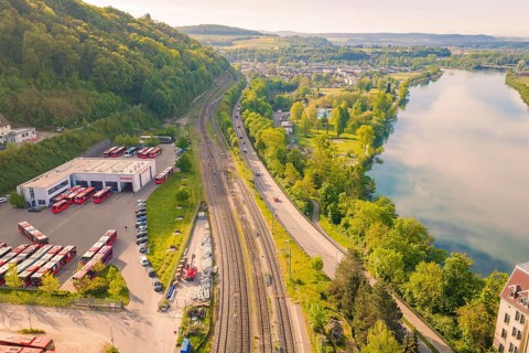 View of train station, river and countryside, green trees and extensive fields in summer,