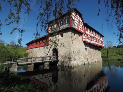 Timbered castle with drawbridge, reflected in water under a clear sky, Hagenwil Castle, Hagenwil,