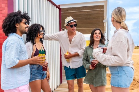 Diverse group of young adult friends enjoying summer vacation, talking, laughing, and drinking