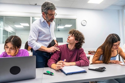 Professor providing individualized assistance and mentorship to a young university student in a