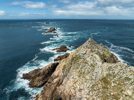 Aerial view of Pointe du Raz with the Phare de la Vieille lighthouse in front of a rocky island,