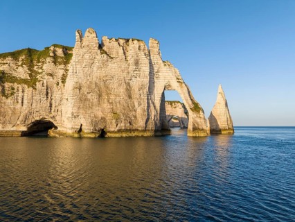 Aerial view of the Porte d'Aval rock formation shortly after sunrise, well-known landmark on the