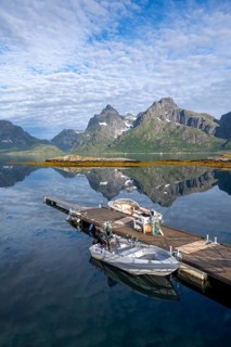 Boats on a jetty, picturesque fjord landscape at Raftsund fjord, mountains reflected in the water,