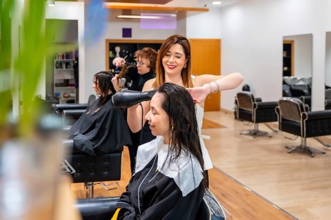 Hairdresser blow drying client's wet hair in a modern salon, providing professional styling and