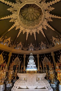 Glass Buddha statue surrounded by figures as heavenly beings and temple guards in the public prayer