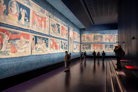 Museum visitors, tourists look at the illuminated, colorful image segments of the historic
