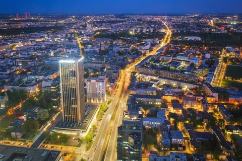 Broad view across the Warsaw skyline in Poland with skyscrapers, city lights, nightfall color, blue
