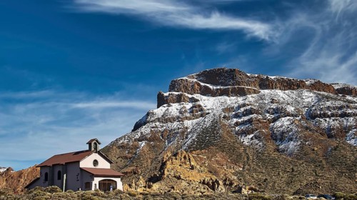 Ermita de las Nieves, church against snowy mountains under blue sky and clouds, Teide, Parque
