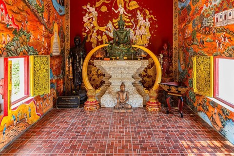 Small prayer room with various Buddha figures framed with elephant tusks, Buddhist temple complex