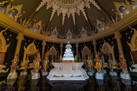 Glass Buddha statue surrounded by figures as heavenly beings and temple guards in the public prayer