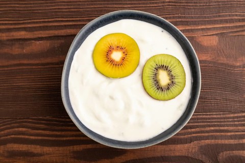 Yogurt, with kiwi in blue bowl on brown wooden background, top view, flat lay, close up, minimalism