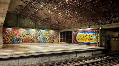 Colourful wall art in a modern subway station, with graffiti and illuminated grids on the ceiling,