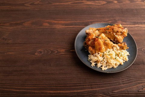 Fried Turkey Wing with spices and rice on plate on brown wooden background. side view, copy space