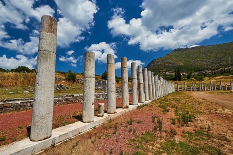 Historic column ruins lead in front of a mountain under a blue sky, Messene Stadium, Ancient Site,