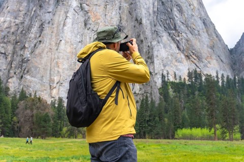 Hiker with a backpack and a camera capturing the scenic view of el capitan, enjoying outdoor