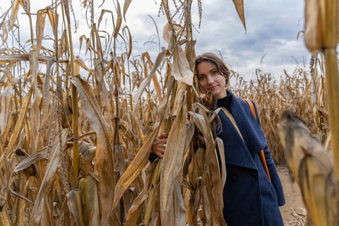 Woman standing in autumn in cornfield and looking at camera