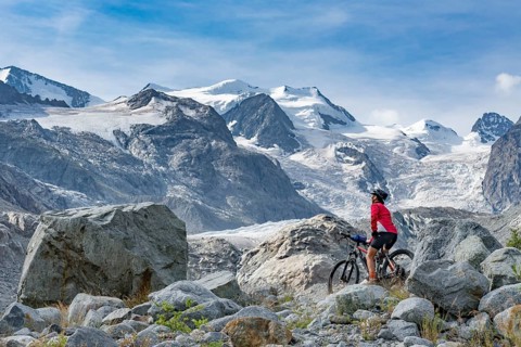 Active senior woman, riding her e-mountain bike in the Morteratsch valley below the glaciers and