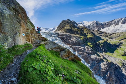 Mountaineers on a narrow hiking trail in front of picturesque high alpine mountain landscape with