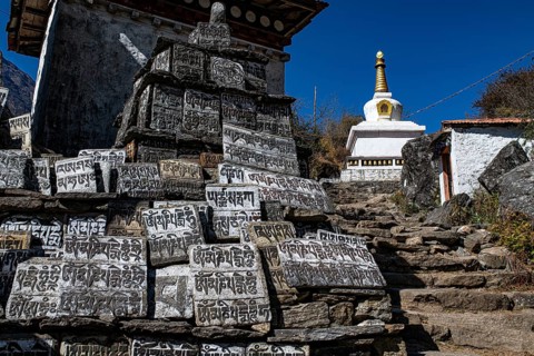 Buddhist manistones with sacred mantras and holy stupa, including choirs, in front of a mountain