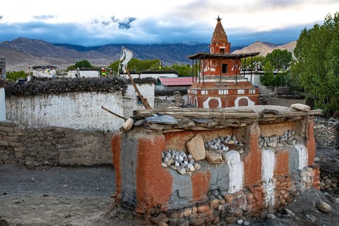 Buddhist stupa, also chords, painted in the foreground on clay wall with Buddhist colors red,