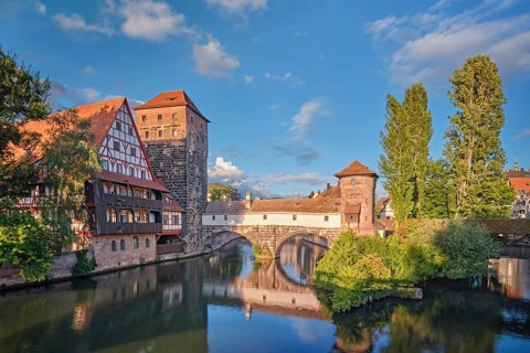 Beautiful reflections of the historic Henkersteg bridge and half-timbered houses in the Pegnitz