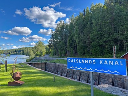 Dalslands canal sign against wooded background and river. Clear sky with few clouds, Dals-Rostock,