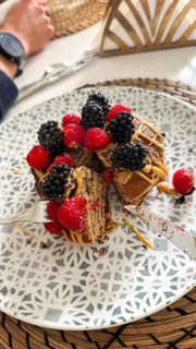 Stack of fluffy homemade pancakes topping with fresh raspberries, blackberries, and creamy peanut