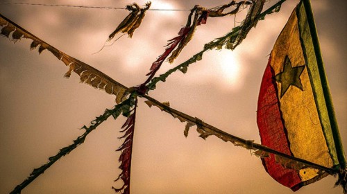 Colourful flags flying on a rope, flag of Senegal, Senegalese flag against an orange sky at sunset,