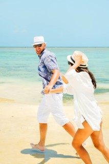 Cheerful young man leading woman couple holding hands run to beach have fun together on shallow