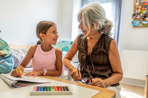 Grandmother and granddaughter bonding, sharing creative moments while drawing at a table,