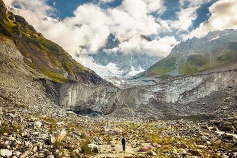 Aerial view woman hiker visit stand by famous hiking destination - Svaneti Shkhara glacier. Summer