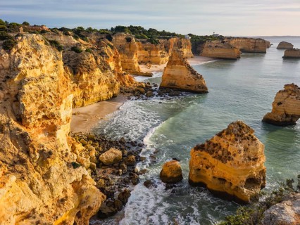 Sunrise view of Praia da Marinha beach in Algarve, Portugal, with golden cliffs, sea stacks,