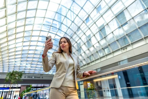 Professional woman holding a smartphone, capturing a moment in a modern building with a distinct