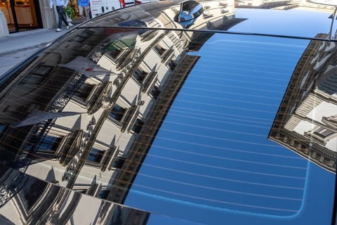 Reflection of a residential building in the rear window of a parked car, Florence, Italy