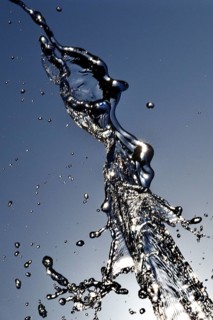 Water frozen by short exposure moving in backlight in front of the sun