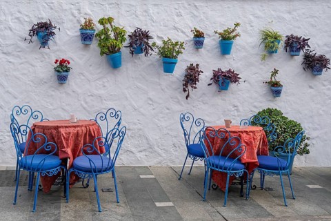 Street cafe with blue outdoor furniture and blue flower pots on a white wall in a Mediterranean