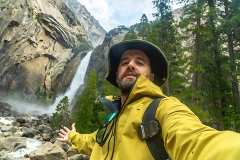 Man in a yellow jacket and hat taking a selfie, capturing himself enjoying the powerful lower