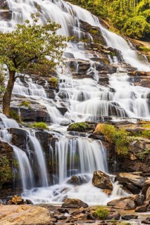 Mae Ya waterfall with cascading flowing water surrounded by lush tropical vegetation, near Doi