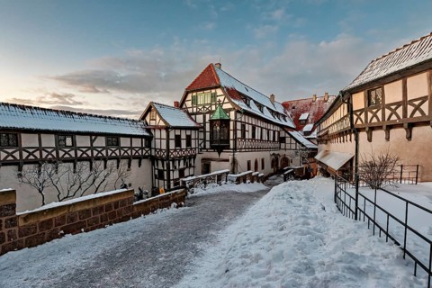 Courtyard of a historic castle in winter, half-timbered buildings in the evening light with snow,