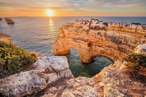 Sunrise view of Praia da Marinha beach in Algarve, Portugal, with a limestone sea arch, Atlantic
