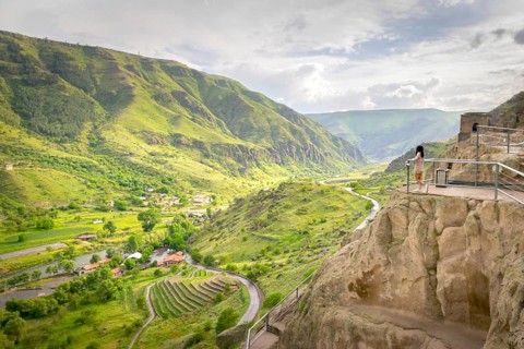 Female tourist enjoys stunning panoramic landscape view from Vardzia viewpoint. Georgia