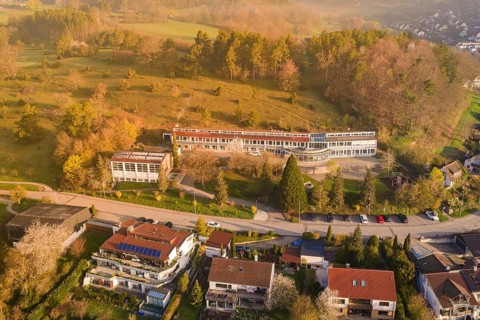 Aerial view shows a school and residential buildings nestled in green surroundings, Deufringen,