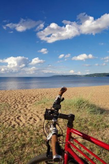 Red bike in front of a beach with a view of the sea and a clear sky, bicycle tours, cycle tourism,
