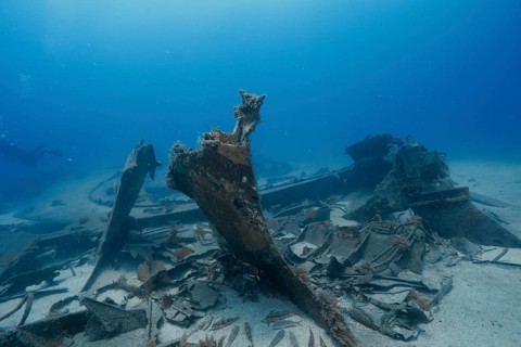 Rusted metal parts of a shipwreck rest on the sandy seabed, meteor wreck dive site, Russian