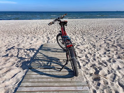 Bicycle standing on a wooden path on a sunny beach with a view of the sea and the blue sky, bicycle