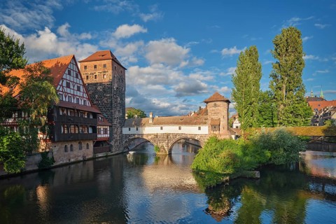Golden sunset light illuminating the Henkersteg bridge and historical buildings on the Pegnitz